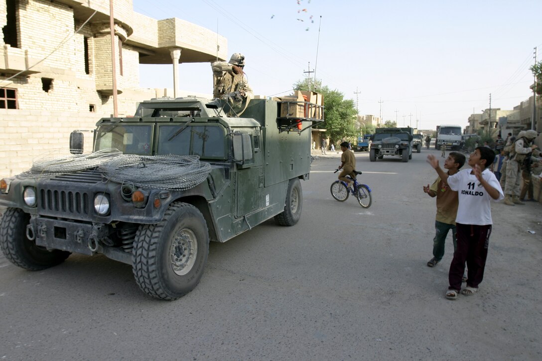 FALLUJAH, Iraq - Lance Cpl. Lionel Clemons, an infantryman with 4th Combined Anti-Armor Team, Weapons Company, 1st Battalion, 6th Marine Regiment, tosses some candy out to local children during a recent patrol.   Fourth CAAT Marines routinely patrol Fallujah's streets aboard their armored trucks and on foot to deter insurgent activity and interact with the community.