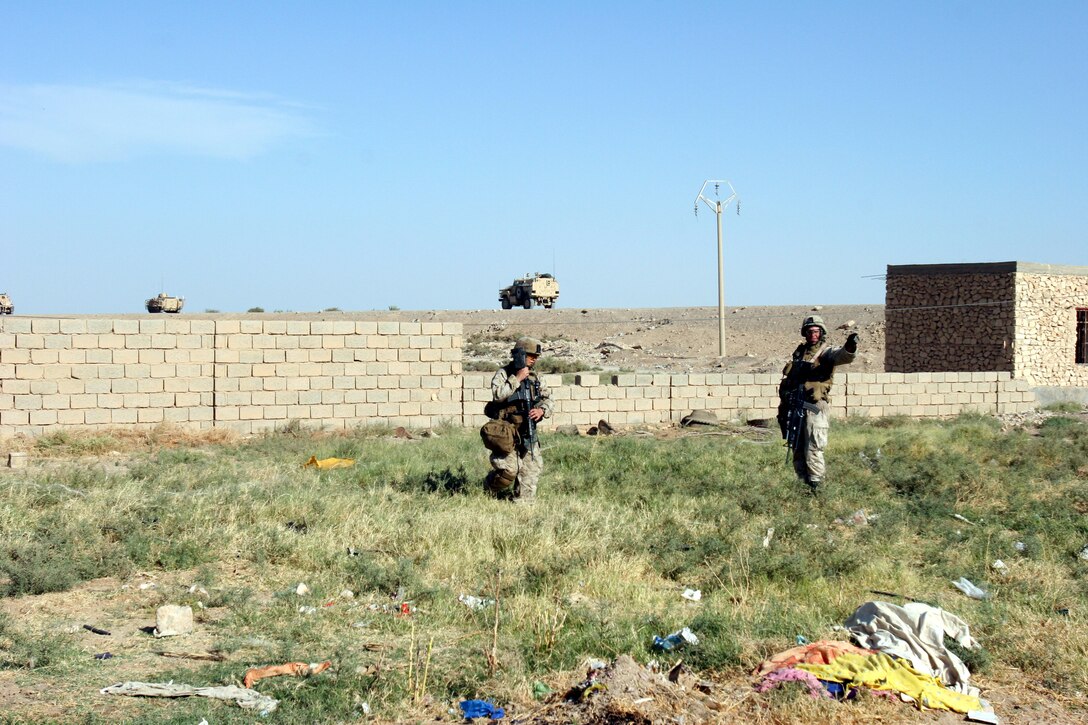 AR RAMADI, Iraq (October 4, 2005) - Two Marines search through a field for hidden weapons caches and explosives during Operation Bowie Oct. 4. The operation was a cooperative effort between the Iraqi Security Force, the army and the Marine Corps to capture and disrupt insurgent activities in Ar Ramadi in the weeks leading up to constitutional election. Photo by Cpl. Shane Suzuki