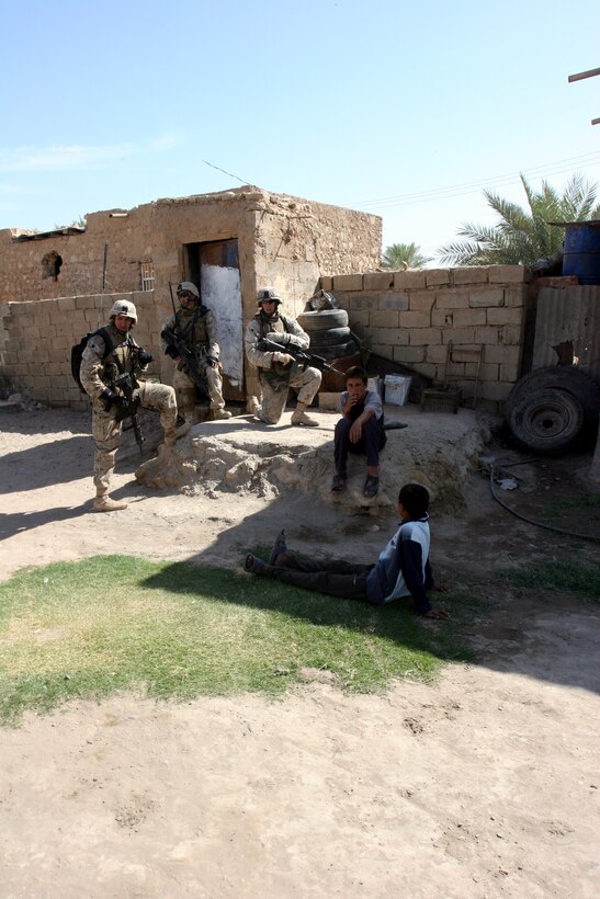 AR RAMADI, Iraq (October 4, 2005) - Three Marines talk with some Iraqi children during Operation Bowie Oct. 4. In addition to the search for insurgent weapons and personnel, the Marines of 3/7 spent time talking with the local populace to gain information on local enemy activities. Photo by Cpl. Shane Suzuki