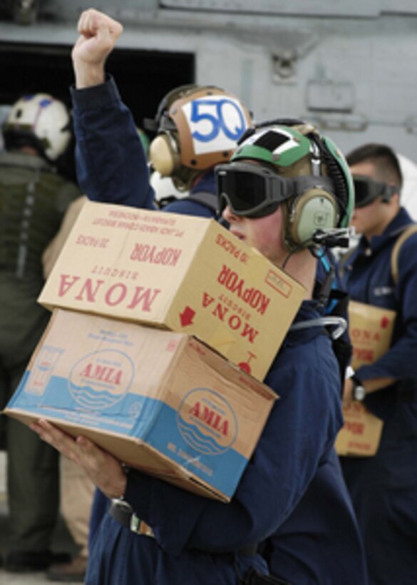 A U.S. Navy sailor from the USS Abraham Lincoln Strike Group tells his shipmates to temporarily halt the transferring of supplies from a truck to an awaiting helicopter in Sumatra, Indonesia, on Jan. 3, 2005. The USS Abraham Lincoln (CVN 72) and its embarked Carrier Air Wing Two 2 are conducting humanitarian operations in the wake of the Dec. 26th tsunamis that struck Southeast Asia as part of Operation Unified Assistance. The Abraham Lincoln Carrier Strike Group is operating in the Indian Ocean off the coasts of Indonesia and Thailand. 