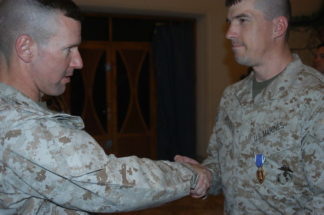 CAMP HURRICANE POINT, Ar Ramadi, Iraq (April 5, 2005) - Major Benjamin B. Busch, team leader, 5th Civil Affairs Group, 1st Battalion, 5th Marine Regiment, shakes hands with his battalion commander, Lt. Col. Eric M. Smith, after being awarded the Purple Heart during a ceremony in the conference room here. The 36-year-old from Sherburne, N.Y., took shrapnel to the right arm from an improvised explosive devise blast. Despite his wounds, Busch returned to full duty the following after being injured.  Photo by Cpl. Tom Sloan