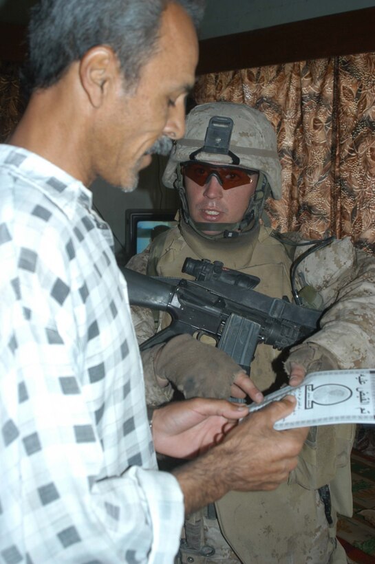 AR RAMADI, Iraq (May 27, 2005) - During a mission in the city here, Staff Sgt. James M. Hussey, the platoon sergeant for 4th Platoon, Company A, 1st Battalion, 5th Marine Regiment, hands an Iraqi man a pro-coalition forces flier and points to a number he can call to report insurgent activity to coalition forces. The 28-year-old from Poughkeepsie, N.Y., led his fellow 4th Platoon warriors on a four-hour aggressive-foot-patrol through several neighborhoods and the city's marketplace. The Marines searched 12 houses and talked to numerous locals during the mission, which was conducted in an attempt to stifle insurgent activity and inform citizens why Marines and coalition forces are occupying Ramadi. The Marines handed out pro-coalition forces and pro-Iraqi government fliers, which had a number to call coalition forces to report insurgent activity. Photo by: Cpl. Tom Sloan
