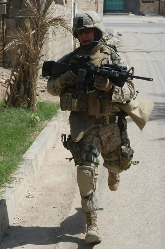 AR RAMADI, Iraq (May 27, 2005) -During a mission in the city here, Staff Sgt. James M. Hussey, the platoon sergeant for 4th Platoon, Company A, 1st Battalion, 5th Marine Regiment, runs down a city street and coordinates his movement with his Marines on his personal radio. The 28-year-old from Poughkeepsie, N.Y., led his fellow 4th Platoon warriors on a four-hour aggressive-foot-patrol through several neighborhoods and the city's marketplace. The Marines searched 12 houses and talked to numerous locals during the mission, which was conducted in an attempt to stifle insurgent activity and inform citizens why Marines and coalition forces are occupying Ramadi. The Marines handed out pro-coalition forces and pro-Iraqi government fliers, which had a number to call coalition forces to report insurgent activity. Photo by: Cpl. Tom Sloan