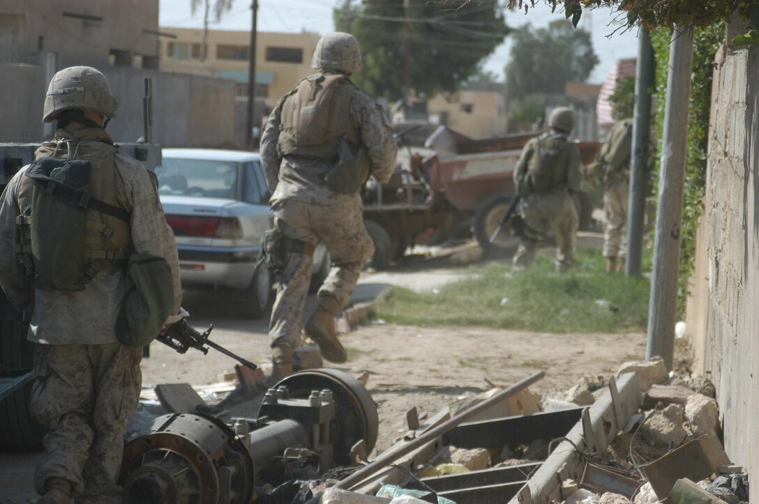 AR RAMADI, Iraq (May 27, 2005) - Four Marines with 4th Platoon, Company A, 1st Battalion, 5th Marine Regiment, move with a sense of urgency along a city street here during a mission. The 4th Platoon warriors conducted a four-hour aggressive-foot-patrol through several neighborhoods and the city's marketplace. The Marines searched 12 houses and talked to numerous locals during the mission, which was conducted in an attempt to stifle insurgent activity and inform citizens why Marines and coalition forces are occupying Ramadi. The Marines handed out pro-coalition forces and pro-Iraqi government fliers, which had a number to call coalition forces to report insurgent activity. Photo by: Cpl. Tom Sloan   .