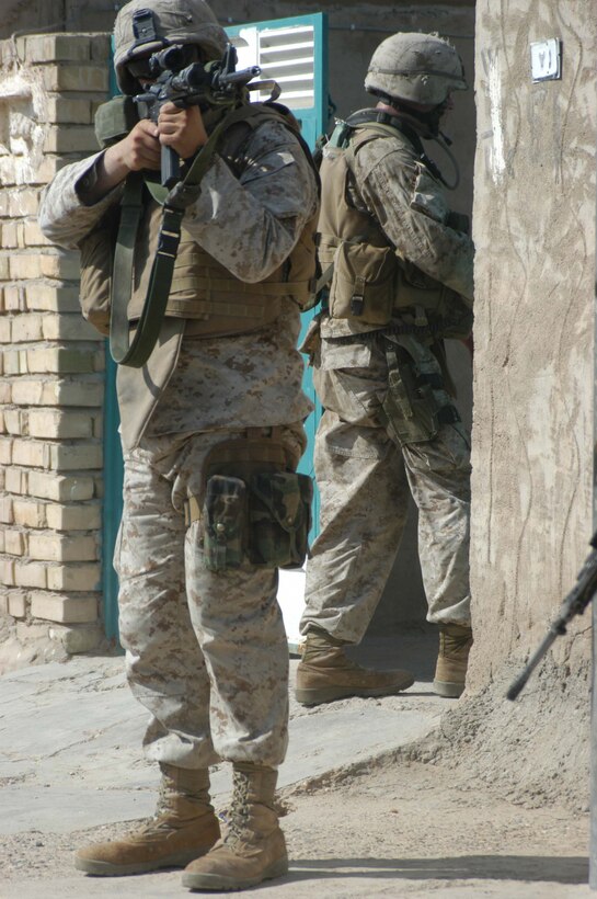 AR RAMADI, Iraq (May 27, 2005) - During a mission in the city here, Lance Cpl. Phillip R. Dunseath, a rifleman with 3rd Squad, 4th Platoon, Company A, 1st Battalion, 5th Marine Regiment, provides security while a fellow Marine passes through the entrance of a residence. The 22-year-old from Donora, Pa., who's in Iraq a third time supporting Operation Iraqi Freedom, and his fellow 4th Platoon warriors conducted a four-hour aggressive-foot-patrol through several neighborhoods and the city's marketplace. The Marines searched 12 houses and talked to numerous locals during the mission, which was conducted in an attempt to stifle insurgent activity and inform citizens why Marines and coalition forces are occupying Ramadi. The Marines handed out pro-coalition forces and pro-Iraqi government fliers, which had a number to call coalition forces to report insurgent activity. Photo by: Cpl. Tom Sloan