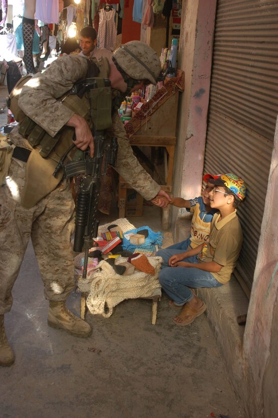 AR RAMADI, Iraq (May 27, 2005) - Lance Cpl. Lewis R. Christman, a grenadier with 3rd Squad, 4th Platoon, Company A, 1st Battalion, 5th Marine Regiment, shakes hands with a young, Iraqi boy while patrolling through the marketplace here. The 23-year-old from Florence, Miss., and his fellow 4th Platoon warriors conducted a four-hour aggressive-foot-patrol through several neighborhoods and the city's marketplace. The Marines searched 12 houses and talked to numerous locals during the mission, which was conducted in an attempt to stifle insurgent activity and inform citizens why Marines and coalition forces are occupying Ramadi. The Marines handed out pro-coalition forces and pro-Iraqi government fliers, which had a number to call coalition forces to report insurgent activity. Photo by: Cpl. Tom Sloan