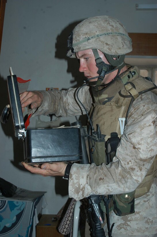 AR RAMADI, Iraq (May 29, 2005) - During a mission in the city here, Cpl. Vernon E. Corbett, a rifleman and squad leader for 3rd Squad, 4th Platoon, Company A, 1st Battalion, 5th Marine Regiment, looks through a box in a house he and his Marines are searching. The 2000 Hickman Mills High School graduate and his fellow squad members searched several houses for weapons caches and questioned residents if they knew of insurgent activity.  Photo by: Cpl. Tom Sloan