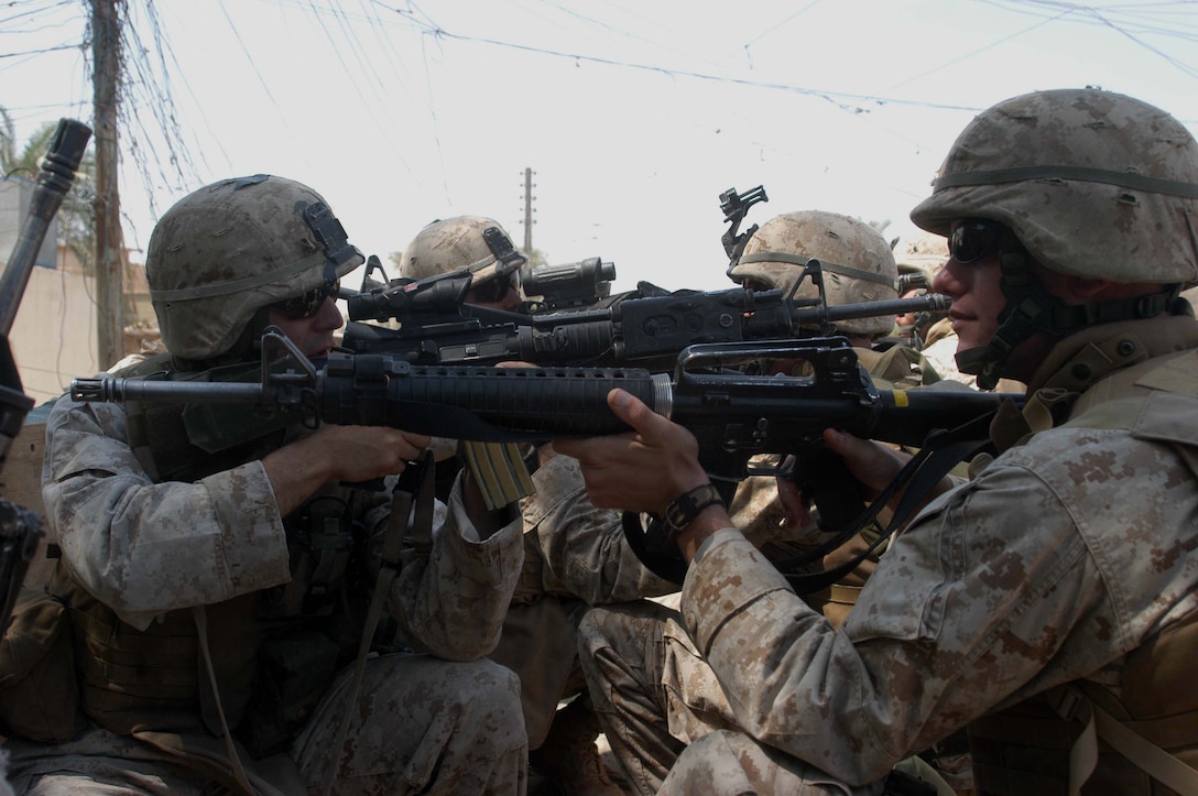 AR RAMADI, Iraq (May 29, 2005) - From the back of a 7-ton truck, Marines with 3rd Squad, 4th Platoon, Company A, 1st Battalion, 5th Marine Regiment, point their weapons and provide security for each other as the vehicle transports them to their destination in the city here. The warriors searched several houses for weapons caches and questioned residents if they knew of insurgent activity. They also conducted a brief patrol through the marketplace where they talked to storeowners and shoppers and questioned them about insurgent activity. Photo by: Cpl. Tom Sloan