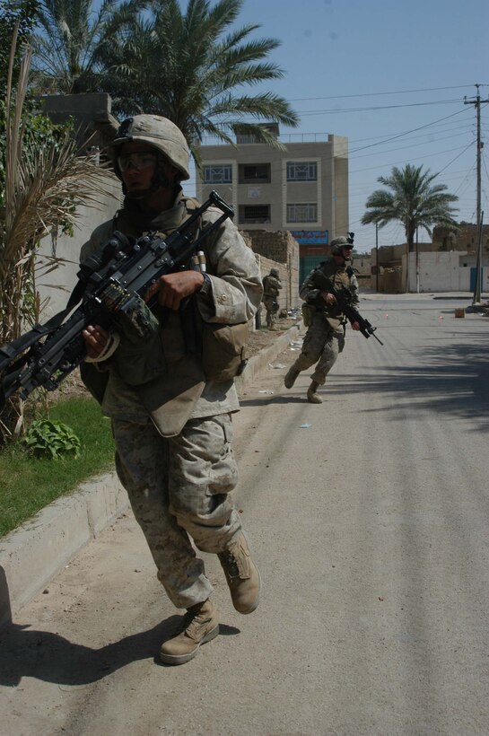 AR RAMADI, Iraq (May 29, 2005) - Lance Cpl. Timothy R. Curridier, a squad automatic machine gunner with 3rd Squad, 4th Platoon, Company A, 1st Battalion, 5th Marine Regiment, runs down a street in the city here during a patrol with his fellow squad members. The 21-year-old from Milwaukee and his fellow squad members searched several houses for weapons caches and questioned residents if they knew of insurgent activity. They also conducted a brief patrol through the marketplace where they talked to storeowners and shoppers and questioned them about insurgent activity. Photo by: Cpl. Tom Sloan