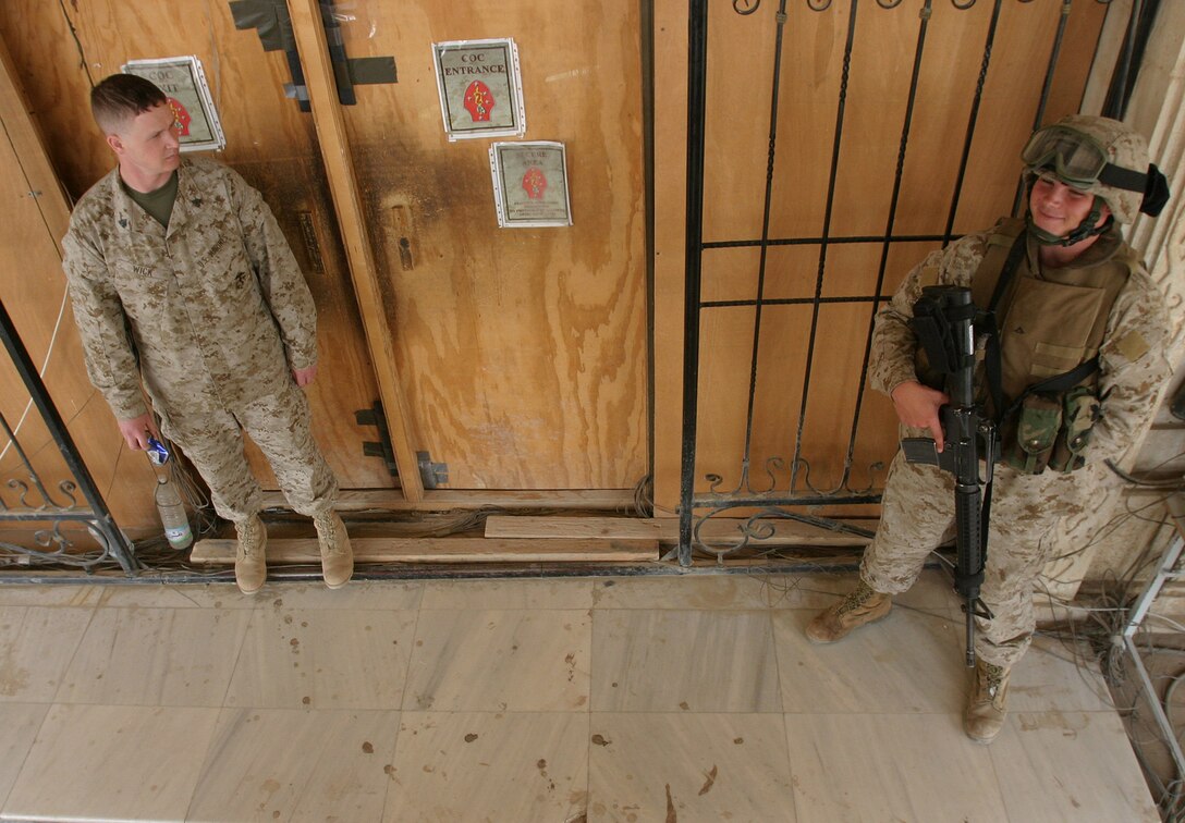 CAMP BLUE DIAMOND, AR RAMADI, Iraq -- Lance Cpl. Paul Jones, a 20-year-old Advanced Field Artillery Tactical Data System operator and sentry on the combat operations center (COC) guard force smiles at Sgt. Jeffrey A. Wick as he exits the COC.  Jones is well-known by all Marines, sailors and soldiers who work here.  That's because they can't get past Jones without a holler and a greeting of the day.  U.S. Marine Corps photo by Sgt. Stephen D'Alessio (RELEASED)
