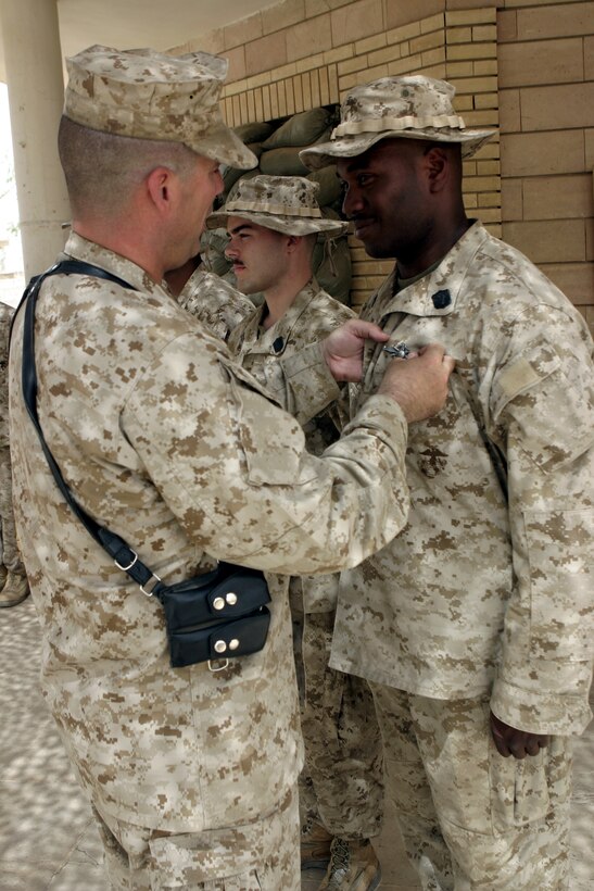 CAMP BAHARIA, Iraq - Hospitalman 3rd Class Troy Antoine, a corpsman with 1st Battalion, 6th Marine Regiment's battalion aid station, is presented with his Fleet Marine Force Warfare pin here July 5.  The 28-year-old Brooklyn, N.Y. native and fellow sailors were recognized for their mastery of Marine concepts, ranging from military history, to weapons employment, to infantry tactics.