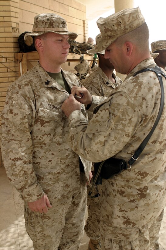 CAMP BAHARIA, Iraq - Hospitalman 1st Class Jeremy Slone, leading petty officer with 1st Battalion, 6th Marine Regiment's battalion aid station, is presented with his Fleet Marine Force Warfare pin here July 5.  The 35-year-old Mendon, Mich. native and fellow sailors were recognized for their mastery of Marine concepts, ranging from military history, to weapons employment, to infantry tactics.