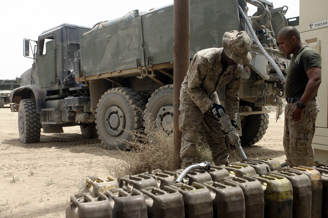 SAQLAWIYAH, Iraq - Lance Cpl. Romaine H. Mullings, a motor transport operator with 1st Battalion, 6th Marine Regiment, refills an infantry base's diesel fuel jugs here July 18.  The 21-year-old West Palm Beach, Fla. native is one of many Marines who perform daily logistics runs to the infantrymen's operational headquarters to re-supply them with water, fuel, and food rations, along with replacing broken appliances and vehicles.