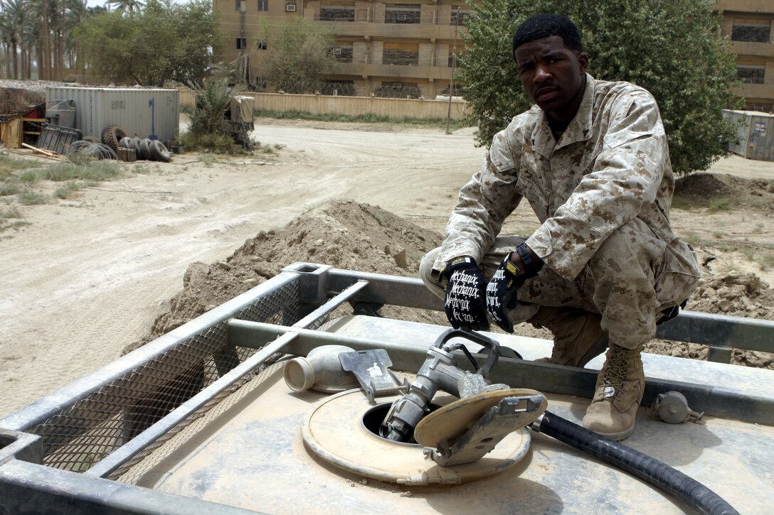 SAQLAWIYAH, Iraq - Lance Cpl. Romaine H. Mullings, a motor transport operator with 1st Battalion, 6th Marine Regiment, refills an infantry base's diesel fuel reserves here July 18.  The 21-year-old West Palm Beach, Fla. native is one of many Marines who perform daily logistics runs to the infantrymen's operational headquarters to re-supply them with water, fuel, and food rations, along with replacing broken appliances and vehicles.