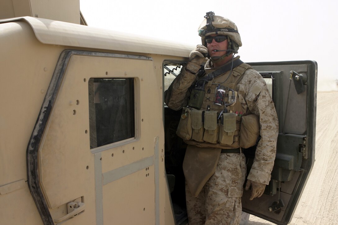 FALLUJAH, Iraq - Gunnery Sgt. Jason Wysocki, 81mm mortar platoon sergeant, Weapons Company, 1st Battalion, 6th Marine Regiment, talks on the radio while escorting a supply and logistics convoy through the city July 18.  81mm mortar platoon Marines provide security for several daily 'log' runs in and around Fallujah to help re-supply the battalion's infantrymen with water, food, and equipment.