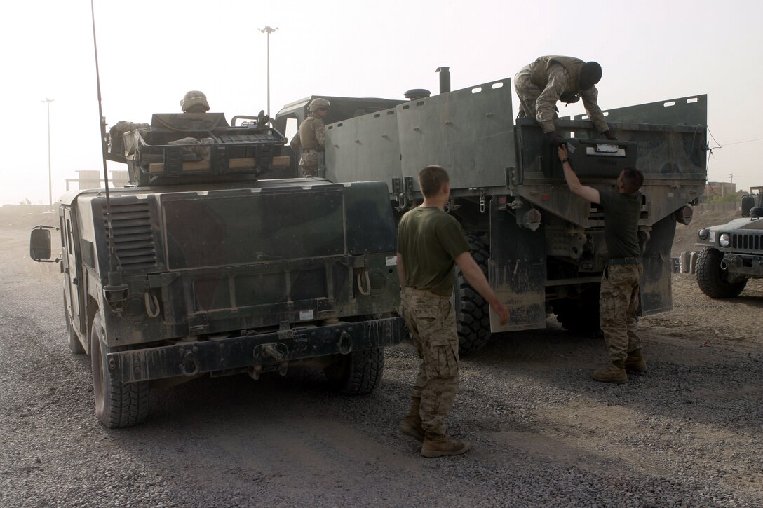 FALLUJAH, Iraq - Marines inside one of the city's entry control points offload vats of chow from a supply truck July 18, as one of the 81mm mortar platoon, Weapons Company, 1st Battalion, 6th Marine Regiment, vehicles provides left flank security.  81mm mortar platoon Marines provide security for several daily 'log' runs in and around Fallujah to help re-supply the battalion's infantrymen with water, food, and equipment.