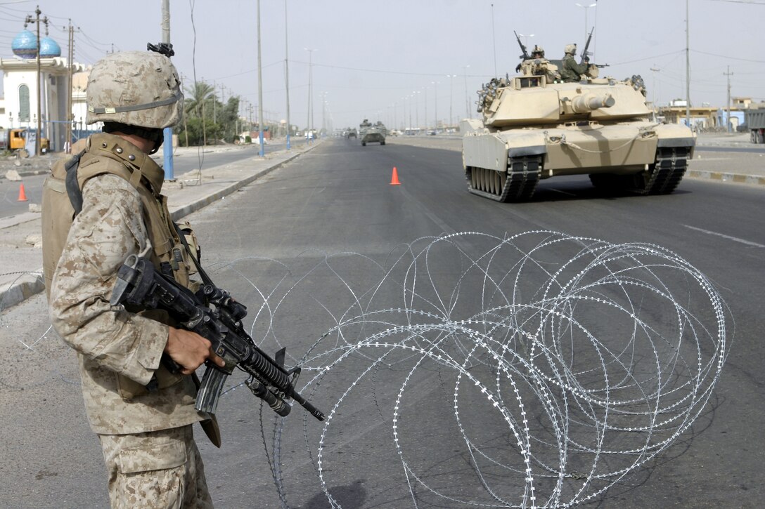 FALLUJAH, Iraq - A Marine with 2nd Combined Anti-Armor Team, Weapons Company, 1st Battalion, 6th Marine Regiment pulls back a strand of concertina wire to let a tank through an intersection here July 19 during Operation Rolling Barrage.  Weapons Company personnel worked alongside 1st Battalion, 6th Marine Regiment infantrymen, Iraqi Security Forces and mechanized supporting elements to block off sections of Fallujah, while roving infantrymen patrolled through the streets to disrupt insurgent activity.