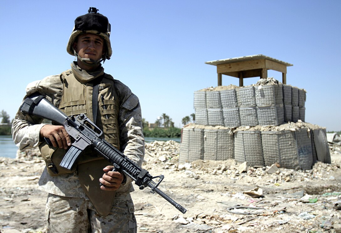 FALLUJAH, Iraq - Corporal Mike Goebel, a combat engineer with 2nd Platoon, Company A, 2nd Combat Engineer Battalion, stands in front of an observation post he and his fellow engineers built along the Euphrates River here Sept. 5.  Iraqi soldiers will man Observation Post Kilpela to monitor the city streets and riverbed's farm fields for insurgent activity, to include the placement of improvised explosive devices.