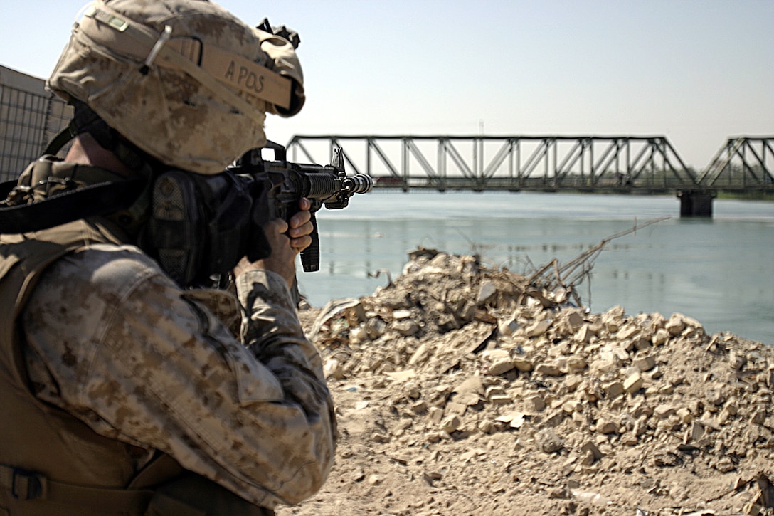 FALLUJAH, Iraq - A Marine with 2nd Platoon, Company A, 2nd Combat Engineer Battalion looks down his rifle's sights as he provides security for fellow Marines erecting a new observation post along the Euphrates River here Sept. 5.  Iraqi soldiers will man Observation Post Kilpela to monitor the city streets and riverbed's farm fields for insurgent activity, to include the placement of improvised explosive devices.