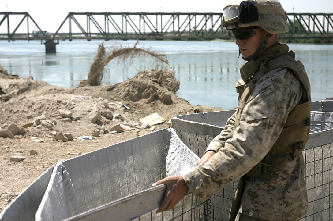 FALLUJAH, Iraq - Lance Cpl. Patrick Jernigan, a combat engineer with 2nd Platoon, Company A, 2nd Combat Engineer Battalion, stretches out barricades to fortify a new observation post he and fellow engineers erected along the Euphrates River here Sept. 5.  Iraqi soldiers will man Observation Post Kilpela to monitor the city streets and riverbed's farm fields for insurgent activity, to include the placement of improvised explosive devices.