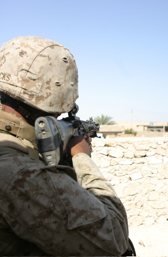 HADITHA DAM, Iraq (Sept. 25, 2005)  - Lance Cpl. Eric L. Hicks Jr., an assualtman with Lima Company, 3rd Battalion, 1st Marine Regiment, provides security from a rooftop here Sept. 25. Hicks and other Marines in his battalion patrolled through the village looking for weapons caches and insurgents who fired on them that day. (Official Marine Corps photo by Cpl. Adam C. Schnell)