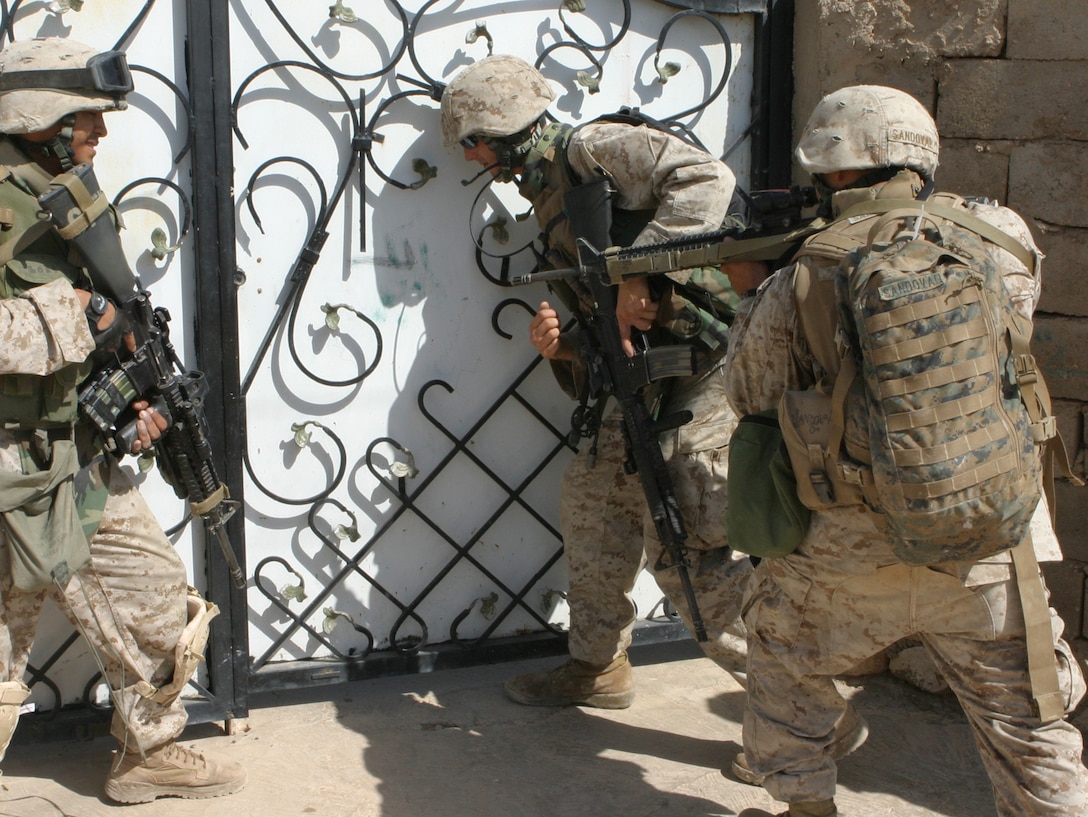 HADITHA DAM, Iraq (Sept. 25, 2005)  - Marines with Lima Company, 3rd Battalion, 1st Marine Regiment, stand outside of a house while searching houses in the village after receiving enemy fire during a patrol her Sept. 25. (Official Marine Corps photo by Cpl. Adam C. Schnell)
