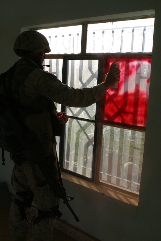 HADITHA, Iraq ? A Marine with 3rd Battalion, 1st Marine Regiment uses spray paint to cover up windows of an abandoned house occupied by Marines Oct. 5. The operation, focused mostly on Haditha, also includes the cities of Haqlaniya and Darwana, where approximately 2,500 U.S. troops and 400 Iraqi security force soldiers clear the city of all insurgent activity.