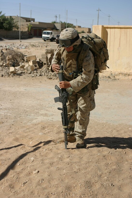 HADITHA, Iraq ? A Marine with Company L, 3rd Battalion, 1st Marine Regiment uses his bayonet to comb through loose dirt piles looking for weapons caches during operations to clear the city here Oct. 5. Met with little resistance, the Marines and Iraqi security force soldiers are clearing the city of the remains of insurgent activities in the area. In only a few days, they have rid the city of many landmines, weapons caches and improvised explosive devices in an effort to take back the town that in the recent past has killed over a dozen U.S. Marines.