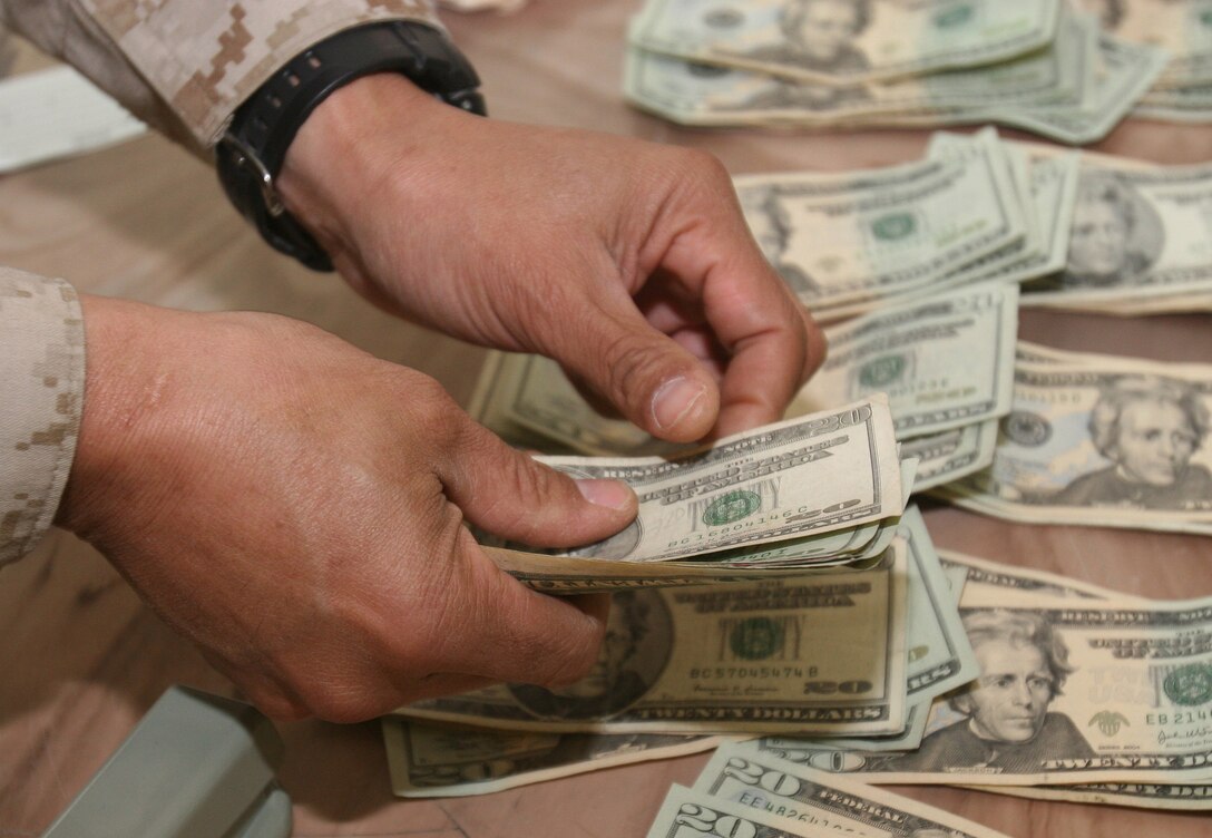 Lieutenant Col. Robert Glover, director of the Al Qaim regional Civil-Military Operations Center, counts out the money in a condolence payment to an Iraqi citizen whose home was damaged in a mortar attack. The CMOC is a function of 6th Civil Affairs Group in Husaybah, Iraq.
