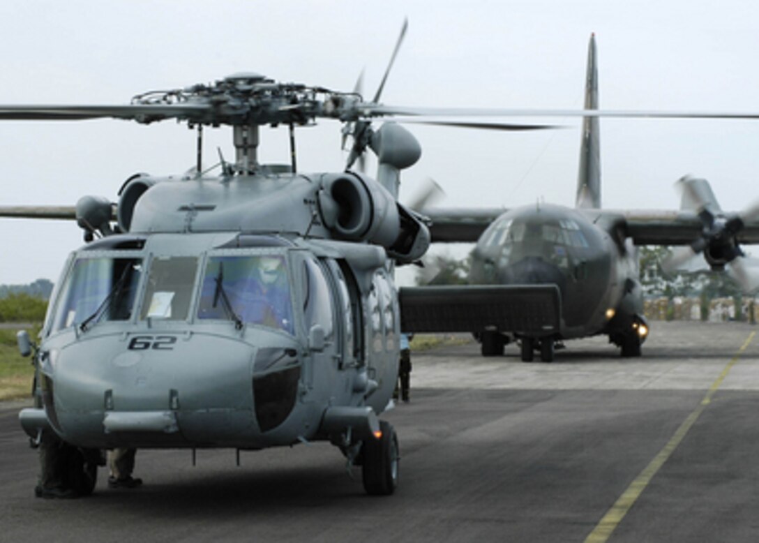 A U.S. Navy SH-60B Seahawk helicopter from the aircraft carrier USS Abraham Lincoln (CVN 72) and an Australian C-130 Hercules prepare for takeoff at Sultan Iskandar Muda Air Force Base in Banda Aceh, Indonesia, to deliver humanitarian relief supplies to the tsunami-stricken regions of Sumatra, Indonesia, on Jan. 3, 2005. The Abraham Lincoln Carrier Strike Group is currently operating in the Indian Ocean off the coasts of Indonesia and Thailand as part of Operation Unified Assistance. 