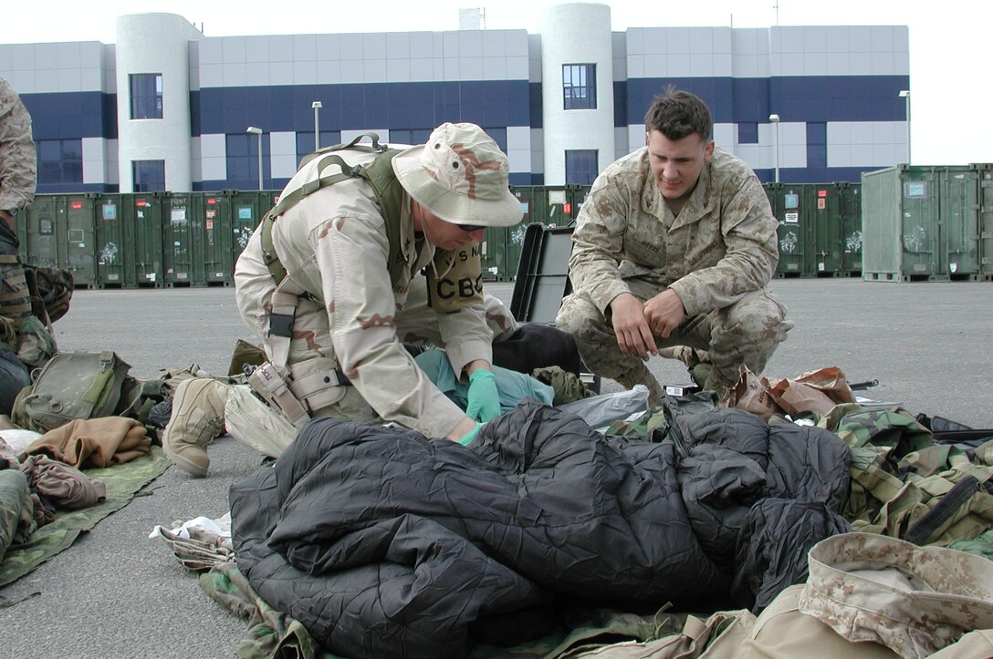 Lance Cpl. Jordan A. Betts, 21, an infantry man with Battalion Landing Team 1/1 and native of Garden Grove, Calif., watches his gear as a customs inspector searches for contraband. The 15th Marine Expeditionary Unit (Special Operations Capable) recently completed their second combat tour in Iraq.