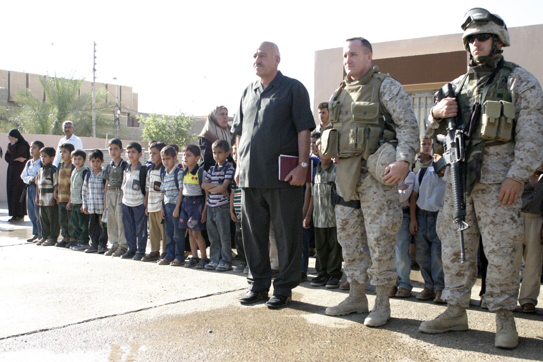 FALLUJAH, Iraq - Lt. Col. William M. Jurney, 1st Battalion, 6th Marine Regiment's commander, stands beside an interpreter and a school faculty member at the Marjan school here May 31, witnessing a presentation the children put on for them in appreciation for helping restore the school.  Jurney was one distinguished guest who witnessed the progress Army civil affairs specialists and local workers had done improving the school by installing new fixtures, doors and electric wiring throughout.