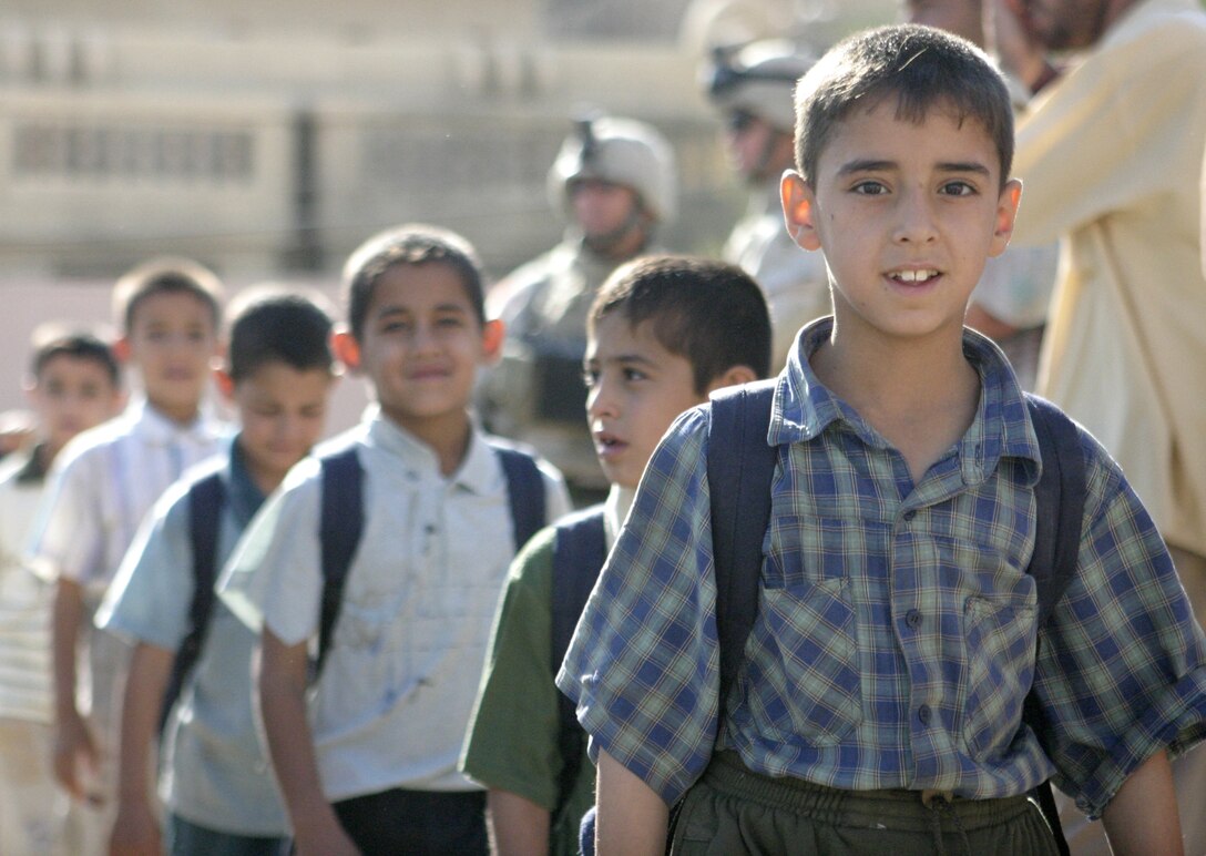 FALLUJAH, Iraq - Army civil affairs specialists stand in the background as children file out of a courtyard at the Marjan school here May 31 after putting on a presentation in appreciation of the soldiers' efforts to restore their school.  Team "Regulators," Company B, 445th Civil Affairs Battalion worked alongside local contractors to install new fixtures, doors and electric wiring throughout the school.