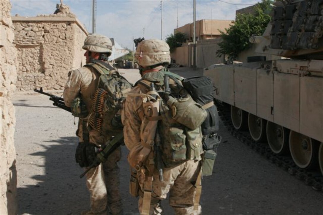 HUSAYBAH, Iraq ? With a Marine Abrams M-1 tank providing coverage, two Marine machine gunners move around a street corner during street fighting here, Nov. 6. The Marines, assigned to 3rd Platoon, Company E, 2nd Battalion, 1st Marine Regiment, and Iraqi soldiers with 1st Battalion, 1st Brigade, 1st Division, Iraqi Army, participated in a joint offensive against insurgents within border towns on the Lower Euphrates River Valley recently.