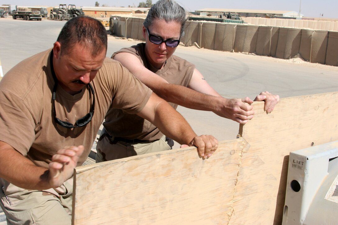 AL ASAD, Iraq ? Petty Officer 2nd Class John Delatore and Petty Officer 3rd Class Adrienne Bott, with Mobile Air Cargo Handling Team 3 work to secure cargo on a pallet at the airfield here June 7. MACH Team 3 is a reserve unit based in Springfield Mo., and has 24 members deployed in support of Operation Iraqi Freedom.