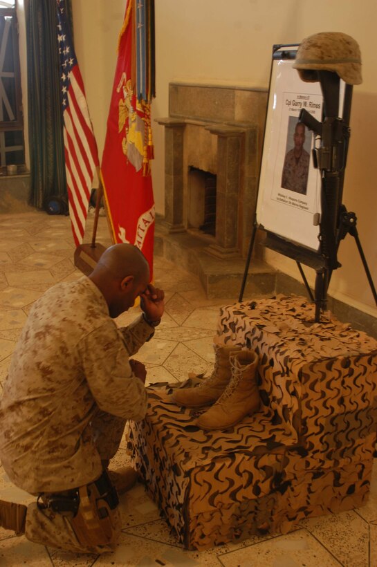 CAMP HURRICANE POINT Ar Ramamdi, Iraq (April 7, 2005) -First Sgt. Dwayne W. Farr, company first sergeant, Company W, 1st Battalion, 5th Marine Regiment, kneels at the foot of a memorial set up for Cpl. Garry W. Rimes. A memorial service was held here for the 30-year-old rifleman and scout with 2nd Platoon, Company W, 1st Battalion, 5th Marine Regiment, who was killed by enemy sniper fire while fighting the Global War on Terrorism. Rimes, from Rizal, Philippines, is survived by his wife, Happy. Photo by Cpl. Tom Sloan