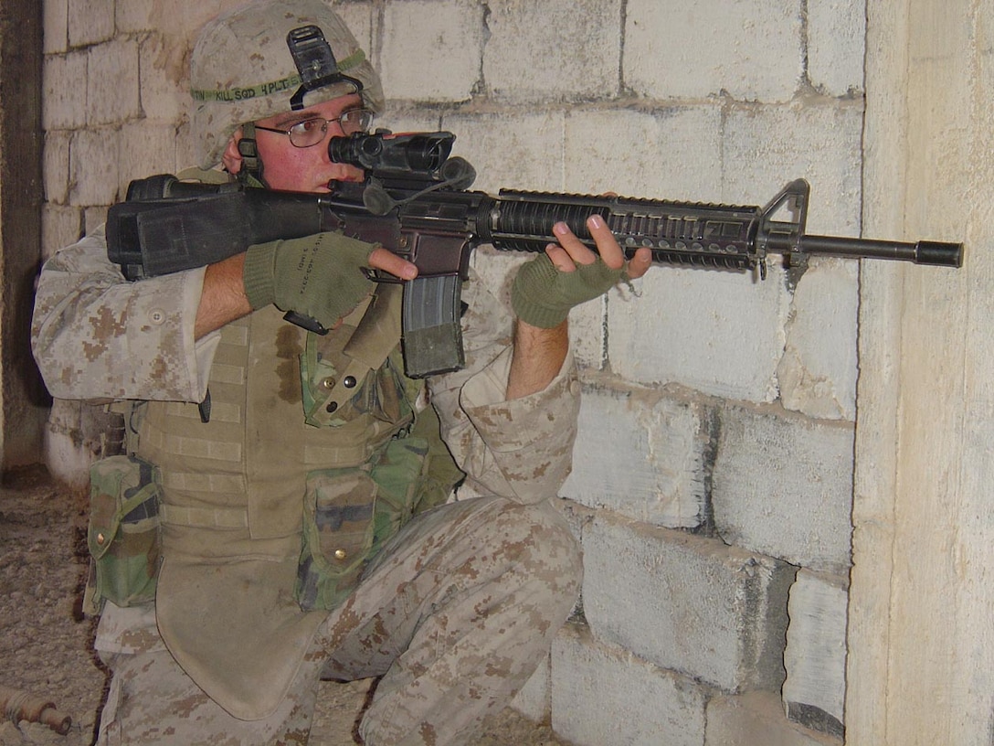 CAMP FALLUJAH, IRAQ -- Lance Cpl. Chuck W. Mikitin, an infantryman with Company K, 3d Battalion, 8th Marine Regiment, takes cover beside a building while checking out the area ahead of him for any possible threats.  Mikitin and  his fellow Marines in his squad patrol regularly through the village and market places of Nasser Wa Salaam.  Official U.S. Marine Corps photo by Lance Cpl. Athanasios L. Genos