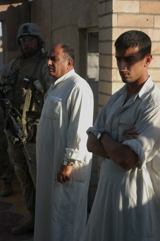 AR RAMADI, Iraq (May 7, 2005) - While conducting an operation here with his fellow Marines, 24-year-old Sgt. Latu L. Puloka, platoon sergeant for 4th Platoon, Company W, 1st Battalion, 5th Marine Regiment, keeps a vigilant watch over two Iraqi men while their house gets searched. The infantry battalion's Company's A, C and W conducted "Operation Weston," which was a three-hour cordon and search mission of a neighborhood. The purpose of the mission was to eradicate the area of insurgents and inform the people living there of the consequences for harboring terrorists. The Marines hit three improvised explosive devises and found one 155 mm shell. One Marine received minor shrapnel wounds, and no insurgents were captured. Photo by Cpl. Tom Sloan