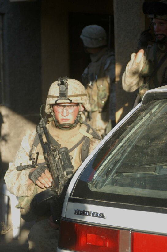 AR RAMADI, Iraq (May 7, 2005) -Lance Cpl. Justin L. Bystrom, a squad automatic gunner with 3rd Squad, 2nd Platoon, Company A, 1st Battalion, 5th Marine Regiment, posts security from behind a parked car during an operation here. The 19-year-old from Parker, Colo., and other warriors with the infantry battalion's Company's A, C and W conducted "Operation Weston," which was a three-hour cordon and search mission of a neighborhood. The purpose of the mission was to eradicate the area of insurgents and inform the people living there of the consequences for harboring terrorists. The Marines hit three improvised explosive devises and found one 155 mm shell. One Marine received minor shrapnel wounds, and no insurgents were captured. Photo by Cpl. Tom Sloan