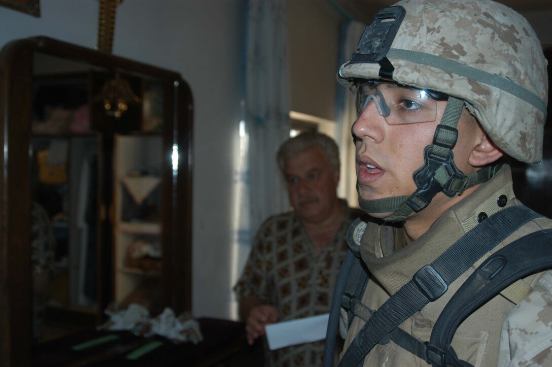 AR RAMADI, Iraq (May 7, 2005) - Corporal Jose L. Villezcas, a rifleman with 3rd Squad, 2nd Platoon, Company A, 1st Battalion, 5th Marine Regiment, seems exhausted after having searched this man's house during a mission here with his fellow Marines. The 21-year-old from Chandler, Ariz., and other warriors with the infantry battalion's Company's A, C and W conducted "Operation Weston," which was a three-hour cordon and search mission of a neighborhood. The purpose of the mission was to eradicate the area of insurgents and inform the people living there of the consequences for harboring terrorists. The Marines hit three improvised explosive devises and found one 155 mm shell. One Marine received minor shrapnel wounds, and no insurgents were captured. Photo by Cpl. Tom Sloan