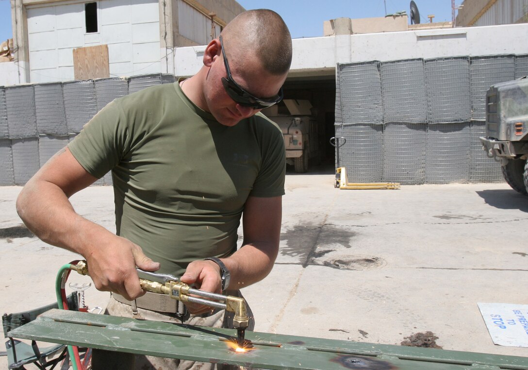 Hadithah Dam, Al Anbar, Iraq.-- Pfc. Bryan L. Sponaugle uses an oxyacetylene welding torch to mend a piece of vehicle armor.  The 20-year-old H&S Company vehicle operator is from Mineral City, Ohio.  Marines are constantly finding new ways to increase protection from IED blasts and small arms fire.  (Photo by LCpl. Marc Fencil. )
