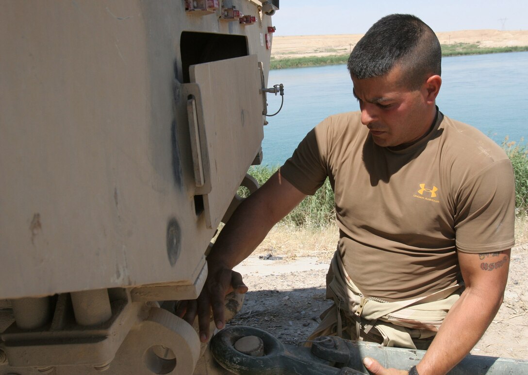Hadithah Dam, Al Anbar, Iraq.-- Cpl. Anthony J. DeSarro attaches a tow bar to a 7-ton truck.  These trucks are used to carry personnel, mail, and other heavy cargo such as sheets of wood.  Due to their larger size, they offer better protection from mines and improvised explosive devices.  (Photo by LCpl. Marc Fencil. )