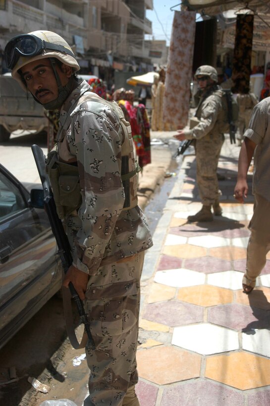 AR RAMADI, Iraq (June 7, 2005) - A member of the Iraqi Security Forces peers down a street in the marketplace here during a mission. Marines with 1st and 2nd Platoon, Company A, 1st Battalion, 5th Marine Regiment, searched several buildings on a mile-long stretch of road that bisects the city's marketplace during "Operation Weatherford III." Two squads of ISF assisted the Marines during the three-hour mission, which was aimed at finding sniper positions, weapons caches, improvised explosive device making material and suspicious individuals. Photo by: Cpl. Tom Sloan