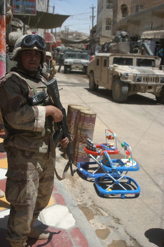 AR RAMADI, Iraq (June 7, 2005) - A member of the Iraqi Security Forces peers down a street in the marketplace here during a mission. Marines with 1st and 2nd Platoon, Company A, 1st Battalion, 5th Marine Regiment, searched several buildings on a mile-long stretch of road that bisects the city's marketplace during "Operation Weatherford III." Two squads of ISF assisted the Marines during the three-hour mission, which was aimed at finding sniper positions, weapons caches, improvised explosive device making material and suspicious individuals. Photo by: Cpl. Tom Sloan