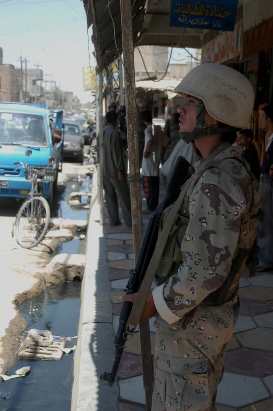 AR RAMADI, Iraq (June 7, 2005) - A member of the Iraqi Security Forces peers down a street in the marketplace here during a mission. Marines with 1st and 2nd Platoon, Company A, 1st Battalion, 5th Marine Regiment, searched several buildings on a mile-long stretch of road that bisects the city's marketplace during "Operation Weatherford III." Two squads of ISF assisted the Marines during the three-hour mission, which was aimed at finding sniper positions, weapons caches, improvised explosive device making material and suspicious individuals. Photo by: Cpl. Tom Sloan