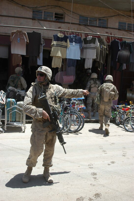 AR RAMADI, Iraq (June 7, 2005) - Lance Cpl. Michael G. Mayberry, a rifleman and team leader with 3rd Squad, 1st Platoon, Company A, 1st Battalion, 5th Marine Regiment, directs his Marines to a position during a mission in the marketplace here. The 24-year-old from Frisco, Texas, and his fellow Company A Marines searched several buildings on a mile-long stretch of road that bisects the city's marketplace during "Operation Weatherford III." Two squads of Iraqi Security Forces assisted the Marines during the three-hour mission, which was aimed at finding sniper positions, weapons caches, improvised explosive device making material and suspicious individuals. Photo by: Cpl. Tom Sloan