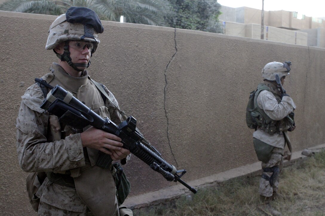 FALLUJAH, Iraq - Lance Cpl. Raleigh Krigbaum, an infantryman with 2nd Platoon, Company B, 1st Battalion, 6th Marine Regiment, provides security alongside fellow Marines here July 7.  The 19-year-old Canton, Ohio native helped fellow infantrymen conduct Operation Hard Knock alongside Security Forces here, during which the troops wired off entire neighborhoods and searched through each house for concealed weapons and explosives.