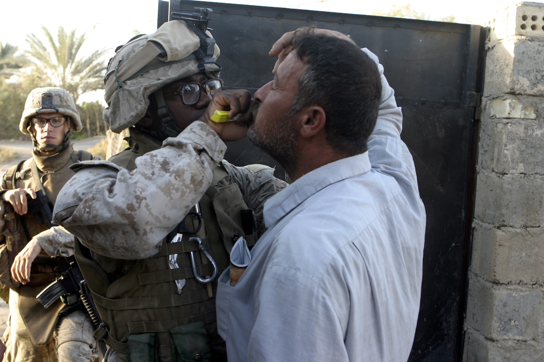 SAQLAWIYAH, Iraq - Seaman Clarence Washington, a corpsman with 4th Platoon, Company A, 1st Battalion, 6th Marine Regiment, treats an Iraqi citizen's eye infection while patrolling the city streets alongside his Marines here July 27.  The 26-year-old Caruthersville, Mo. native is one of several 'docs' who live and work alongside the infantrymen here, administering first aid in combat and treating acute illnesses.