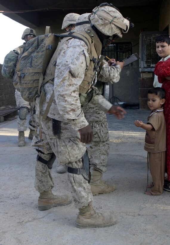 SAQLAWIYAH, Iraq - Seaman Clarence Washington, a corpsman with 4th Platoon, Company A, 1st Battalion, 6th Marine Regiment, hands an Iraqi child some candy while conducting a mission alongside his Marines here July 27.  The 26-year-old Caruthersville, Mo. native is one of several 'docs' who live and work alongside the infantrymen here, administering first aid in combat and treating acute illnesses.