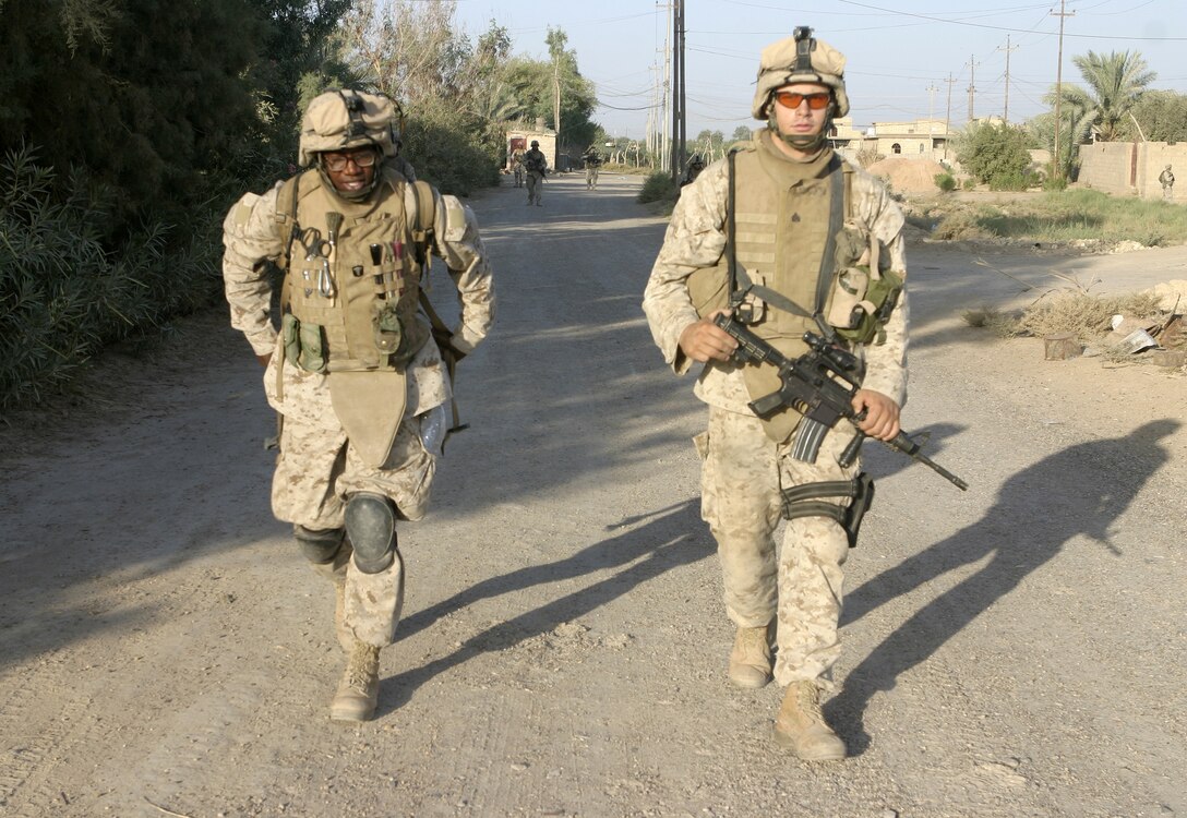 SAQLAWIYAH, Iraq - Seaman Clarence Washington, a corpsman with 4th Platoon, Company A, 1st Battalion, 6th Marine Regiment, left, patrols the town's streets alongside his Marines July 27.  The 26-year-old Caruthersville, Mo. native is one of several 'docs' who live and work alongside the infantrymen here, administering first aid in combat and treating acute illnesses.